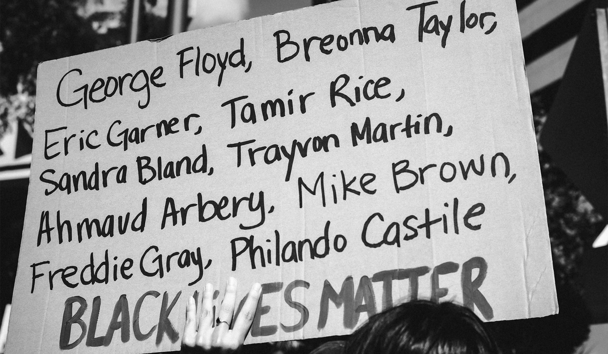 A protest sign featuring the names George Floyd, Breonna Taylor, Eric Garner, Tamir Rice, Sandra Bland, Trayvon Martin, Ahmaud Arbery, Mike Brown, Freddie Gray, and Philando Castile above the words Black Lives Matter.